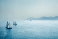 Sailing regatta or a group of small water racing boats and helicopter in the Mediterranean, a panoramic view with blue mountains o Royalty Free Stock Photo