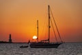 Sailboats at sunset anchored in the bay near the lighthouse.