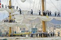 Sailors setting sails of three masted ship on foggy day