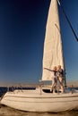 Sailing around world. Full length of happy senior couple standing on the side of sail boat or yacht deck floating in sea Royalty Free Stock Photo