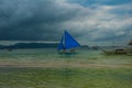 Sailing boat with a blue sail on a background of clouds , Boracay island, Philippines Royalty Free Stock Photo