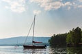 Sailing boat in the lake in the evening sunlight over the beautiful big mountains background, luxury summer adventure Royalty Free Stock Photo