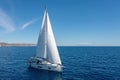 Sailing boat with open white sails, blue sky and rippled sea background Royalty Free Stock Photo