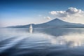 sailing boat passing through calm waters, with majestic mountains in the background