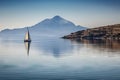 sailing boat passing through calm waters, with majestic mountains in the background