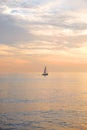 A sailing boat silhouetted in a calm seamless orange glowing sea Royalty Free Stock Photo