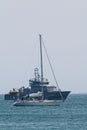 Sailing boat and warship in the open sea