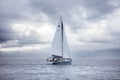 Sailing boat with white sails, cloudy sky and rippled sea background Royalty Free Stock Photo