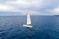 Sailing boat with white sails, cloudy sky and rippled sea background Royalty Free Stock Photo