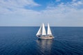 Sailing boat with white sails in the open sea, cloudy blue sky Royalty Free Stock Photo