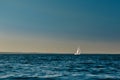 Sailing boat or yacht with open white sails floating on the sea at sunset. Majestic landscape, calm and tranquility Royalty Free Stock Photo