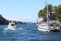 Sailing catamaran sails along the rocky green coast past the red literary sign - the fairway lighthouse. City of Sibenik in the Da