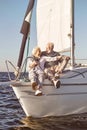 Sailing is a fun. A happy senior couple sitting on the side of a sail boat on a calm blue sea. Man hugging his woman Royalty Free Stock Photo