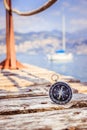 Sailing: nautical compass on wooden dock pier. Sailing boats in the background