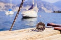 Sailing: nautical compass on wooden dock pier. Sailing boats in the background