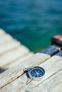 Sailing: nautical compass on wooden dock pier. Sailing boats in the background