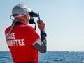 Sailing race referee with binocular and marine VHF radio.