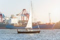 Sailing ship on the Elbe river in Hamburg in front of container ship and harbor in the evening sun Royalty Free Stock Photo