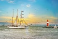 Sailing ship on the sea at sunset. Lighthouse and birds. Royalty Free Stock Photo
