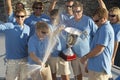 Sailing team celebrating with trophy on boat