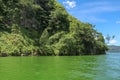 Sailing a traditional fishing boat from the village of Trunyan to a unique cemetery. High mountains covered with dense tropical Royalty Free Stock Photo