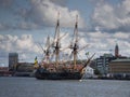 Sailing vessel with flags fluttering in the breeze against the backdrop of a cityscape