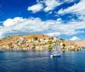 Sailing yacht in the beautiful buildings of Symi island, Greece, clouds, sky, bright Sunny day