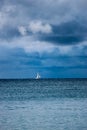 Sailing yacht boat on the sea on horizon under stormy sky with clouds Royalty Free Stock Photo
