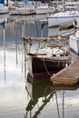 Sailing yacht with folded mast and cabins moored to the pier next to other yachts in the harbor