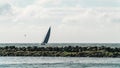 Sailing yacht listing in windy conditions in front of a port