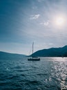 Sailing yacht sails on the sea under bright sunbeams against the backdrop of mountains