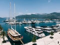 Sailing yacht stands at the pier next to the rows of motor yachts