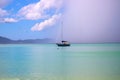 Sailing yacht in turquoise blue sea under rainy cloud. Tropical storm in marine lagoon. Rain cloud on exotic seashore Royalty Free Stock Photo