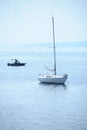 Sailing yacht ride at anchor in the bay, misty shore visible in the distance Royalty Free Stock Photo