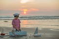 Sailor baby boy, cute child, playing on the beach with wooden boat, fishes and fishing rod on sunset Royalty Free Stock Photo