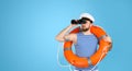 Sailor with binoculars and ring buoy on blue background Royalty Free Stock Photo