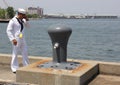 Sailor with a cell phone walking by a large mooring cleat, NY Fleet Week 2012