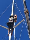 A sailor climbing up to fix the sail boat mast in Kudat, Malaysia. Royalty Free Stock Photo