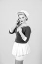Sailor dressed girl with smart-phone isolated on grey background
