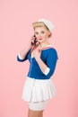 Sailor dressed female with smart-phone on pink background. Blond girl with curls and pin-up make-up talking over cellular