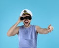 Sailor looking through binoculars and pointing on blue background Royalty Free Stock Photo