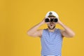 Sailor looking through binoculars on yellow background, space for text Royalty Free Stock Photo