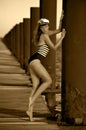 Sailor model in stylish swimsuit and captain hat posing on the wooden pier