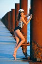 Sailor model in stylish swimsuit and captain hat posing on the wooden pier