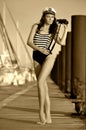 Sailor model in stylish swimsuit holding binoculars and standing on the wooden pier