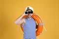 Sailor with orange ring buoy looking through binoculars on yellow background Royalty Free Stock Photo