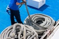 Sailor on the ship is giving mooring in the port. The rope is coiling and wounding in a spiral