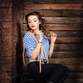 Sailor woman in striped vest and rope sitting on dower chest. wooden background Royalty Free Stock Photo