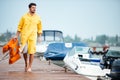 Sailor in yellow cloak at the pier holding life vest Royalty Free Stock Photo