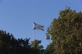 Saint Andrew Andreevsky flag Ensign of the Russian Navy on a flagpole waving the roof of the Admiralty building behind trees